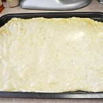 Using your fingers and palms spread the dough on the pan.